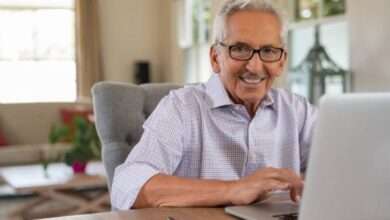 Idoso sentado e sorrindo em frente ao computador