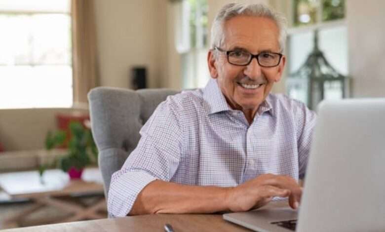 Idoso sentado e sorrindo em frente ao computador