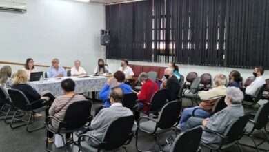 Auditório com pessoas sentadas em reunião, respeitando o distanciamento social