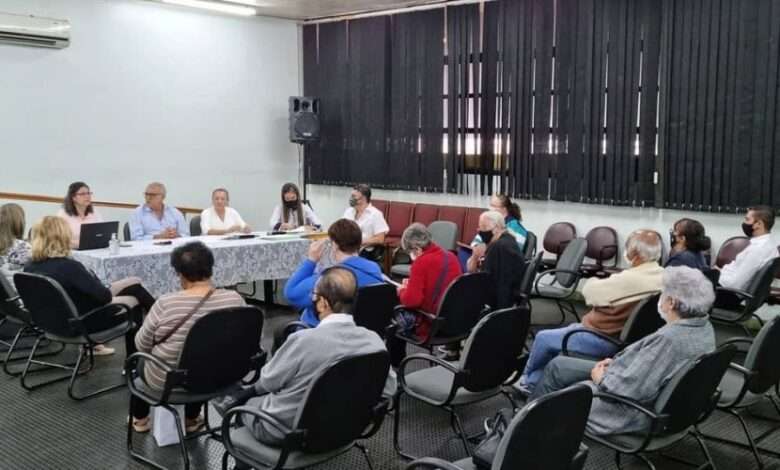 Auditório com pessoas sentadas em reunião, respeitando o distanciamento social