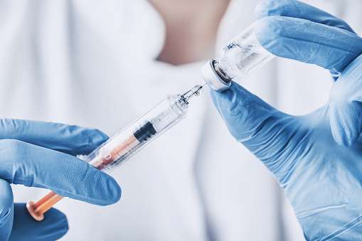 seringa e frasco de vacina nas mãos de um profissional da saúde
