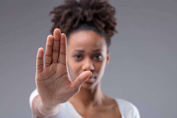 Mulher fazendo sinal de PARE com a mão à sua frente.