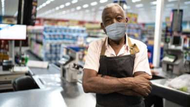 Homem idoso, usando máscara no ambiente de trabalho, que é um supermercado