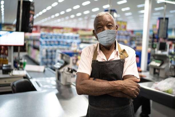 Homem idoso, usando máscara no ambiente de trabalho, que é um supermercado