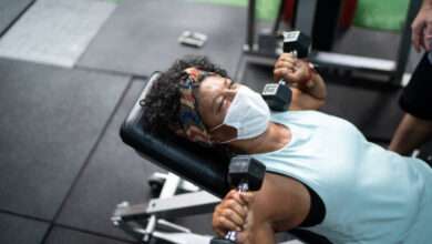 Idosa com máscara facial fazendo exercícios numa academia