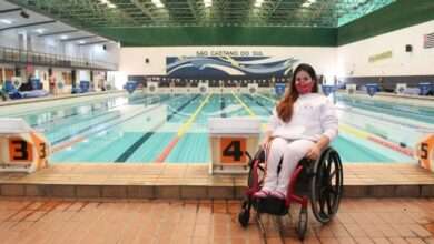 Paratleta Natali Rodrigues da Silva na cadeira de rodas em frente à piscina onde treina em São Caetano do Sul