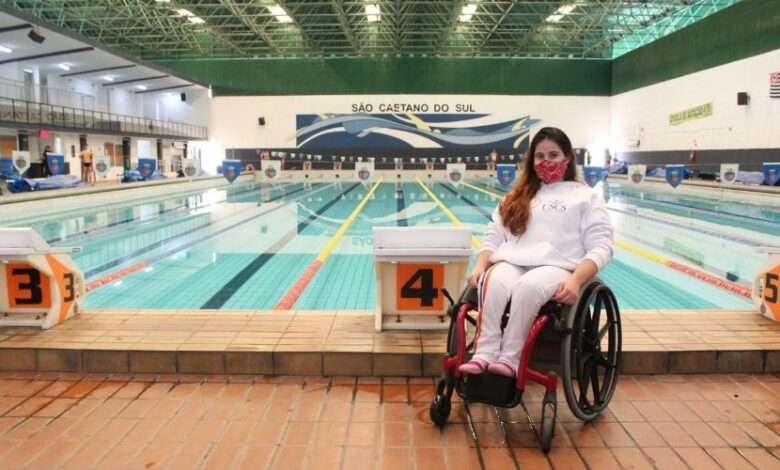 Paratleta Natali Rodrigues da Silva na cadeira de rodas em frente à piscina onde treina em São Caetano do Sul