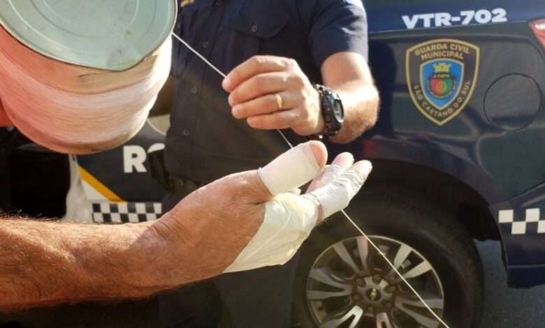 mãos com curativos e GCM segurando linha de pipa com cortante